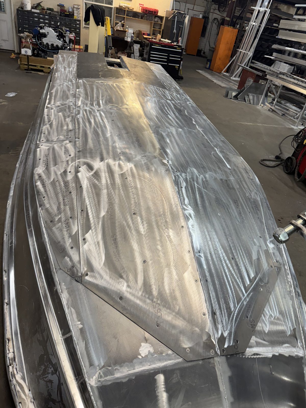A Banshee hull upside down in the shop with bare 7000-series aluminum armor plating on the bottom